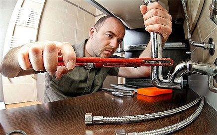 Plumber tightening pipe under sink 