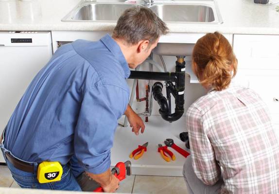 Plumber working with plumber under sink 