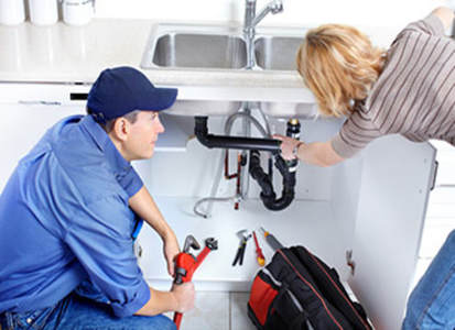 Plumber and woman fixing sink 